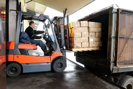 Man on forklift loading container at distribution center